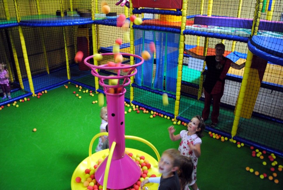 Kinder spielen in einem Indoor-Spielplatz mit einer Ballfontäne.