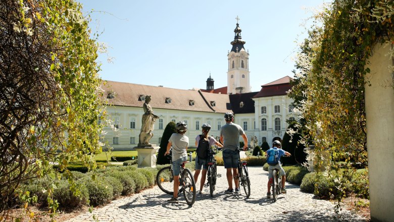 Familie mit Fahrr&auml;dern vor einem historischen Geb&auml;ude mit Turm.