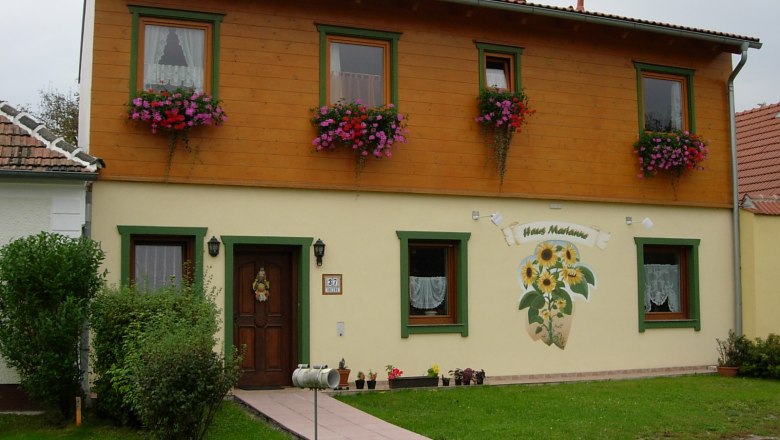TD, Haus Marianne, Pischelsdorf, Hausansich, © Reiter Zweistöckiges Haus mit Holzverkleidung und Blumenkästen, beschriftet als 'Haus Marianne'.