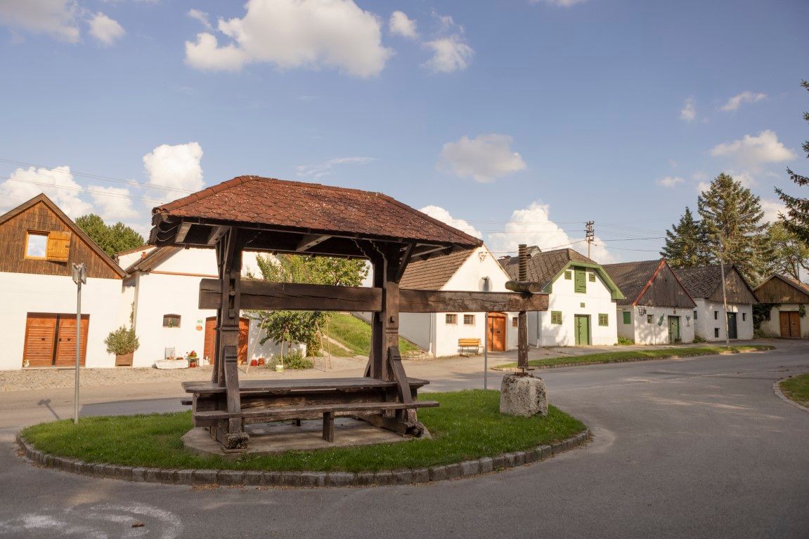 Historische Weinpresse in Kettlasbrunn vor traditionellen Kellergassenhäusern.