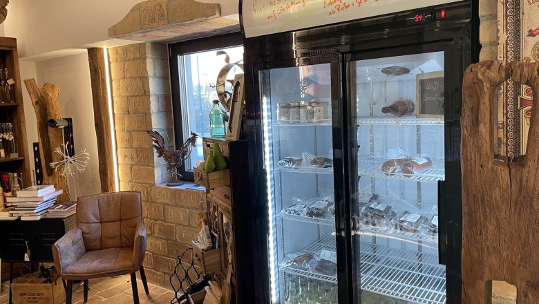 Innenansicht eines Ladens mit Kühlschrank, Stuhl und Dekorationen.