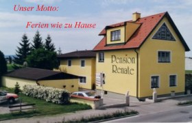 Gelbes Gebäude mit der Aufschrift 'Pension Renate', umgeben von Bäumen und einem Parkplatz.