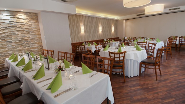 Elegantes Restaurant mit gedeckten Tischen und grünen Servietten.