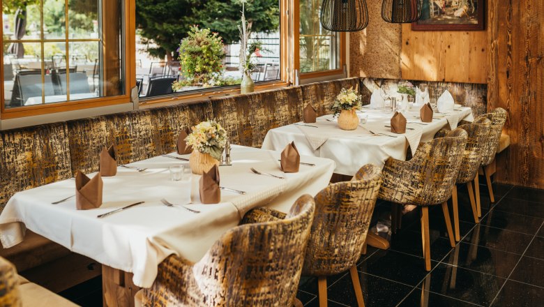 Gem&uuml;tliches Restaurant mit gedeckten Tischen, Blumen und rustikalem Ambiente.