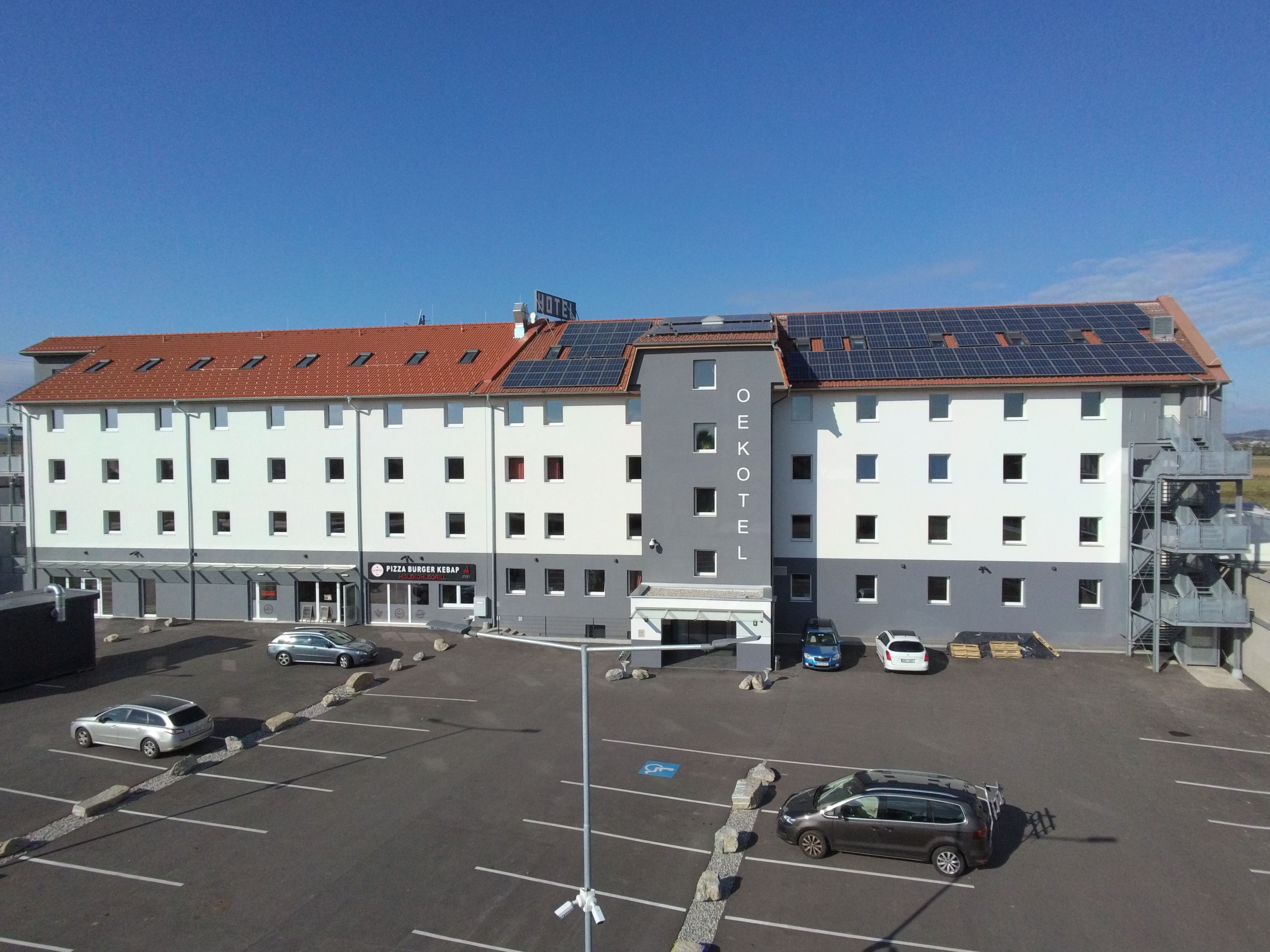 OEKOTEL Föhrenhain mit Solarpanelen auf dem Dach und Parkplatz davor.