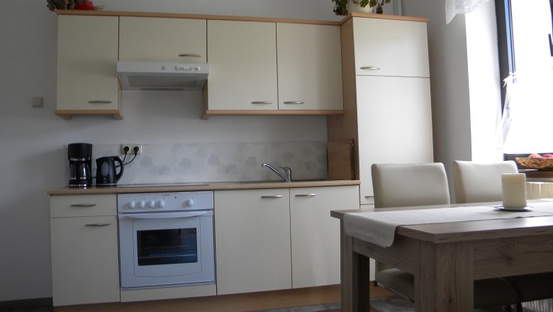 Moderne Küche mit cremefarbenen Schränken, Esstisch und Stühlen.