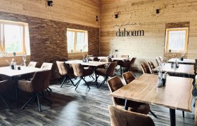 Gem&uuml;tlicher Gastraum aus hellem Holz mit braunen St&uuml;hlen und Holztischen.