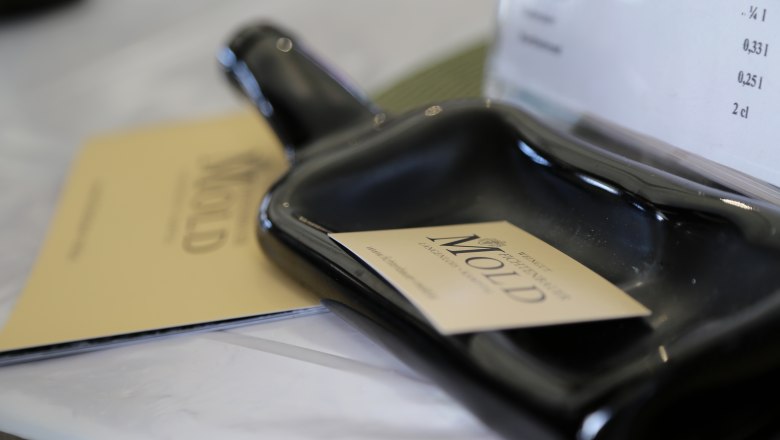 Nahaufnahme eines schwarzen Keramikgef&auml;&szlig;es mit einer Visitenkarte des Weinguts Mold darauf.