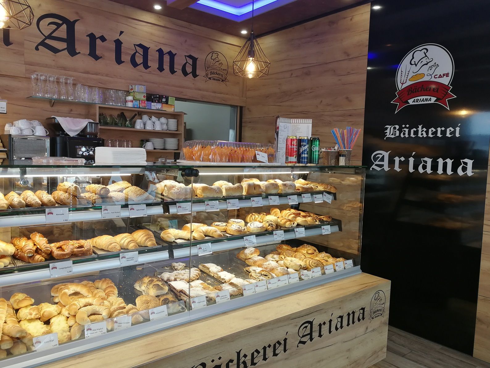 Innenansicht der Bäckerei Ariana mit einer Auslage voller Backwaren.