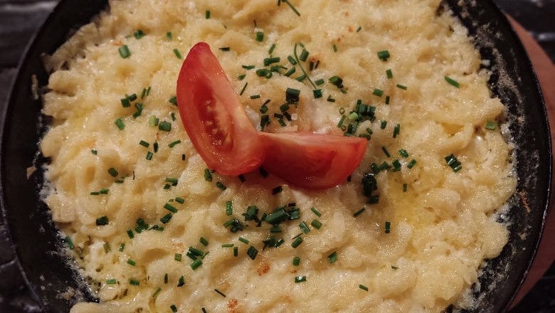 Eine Pfanne mit K&auml;sesp&auml;tzle, garniert mit Tomaten und Schnittlauch.