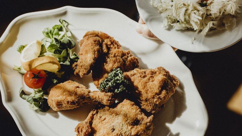 Ein Teller mit paniertem Backhendl, Salat und Zitrone.
