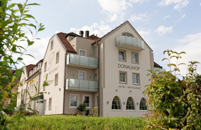 Außenansicht des Hotel Restaurant Donauhof mit Balkonen und Garten.