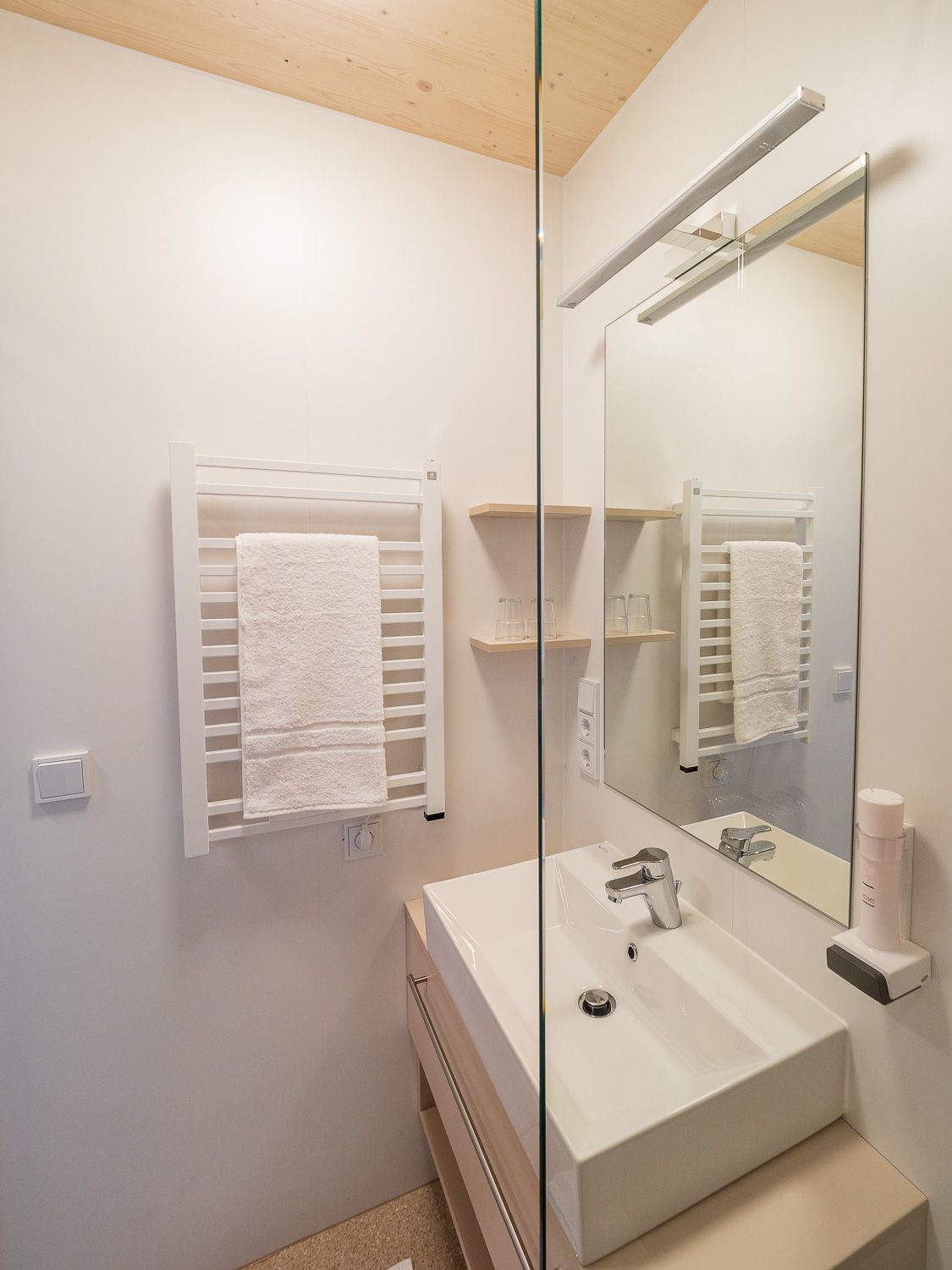 Modernes Badezimmer mit Waschbecken, Spiegel und Handtuchhalter.