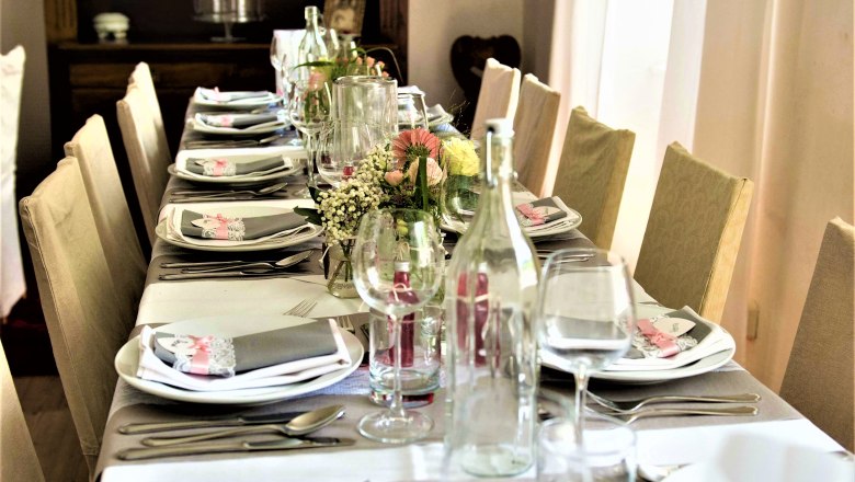 Festlich gedeckter Tisch mit Blumen und Geschirr im H&ouml;blinghof.