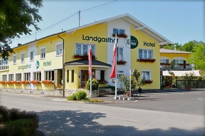 Gelbes Landgasthof-Hotel mit Blumenkästen und österreichischen Flaggen.