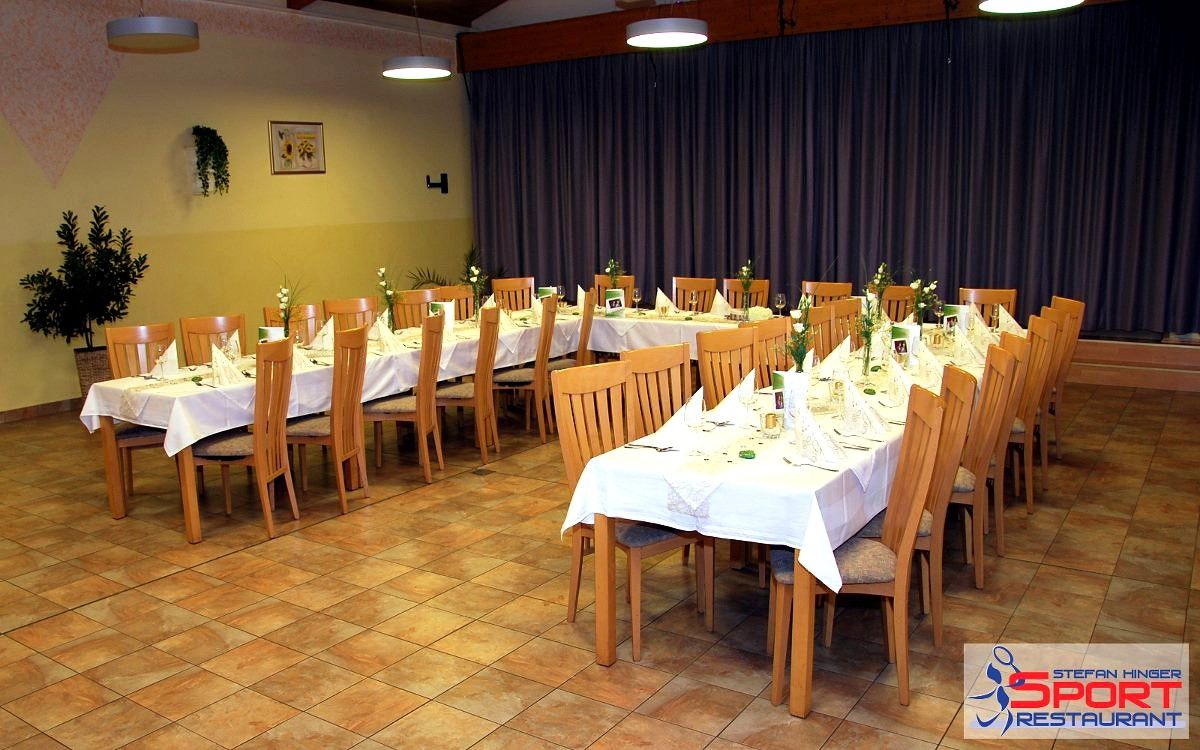 Ein festlich gedeckter Tisch in einem Restaurant mit Holzstühlen und weißen Tischdecken.