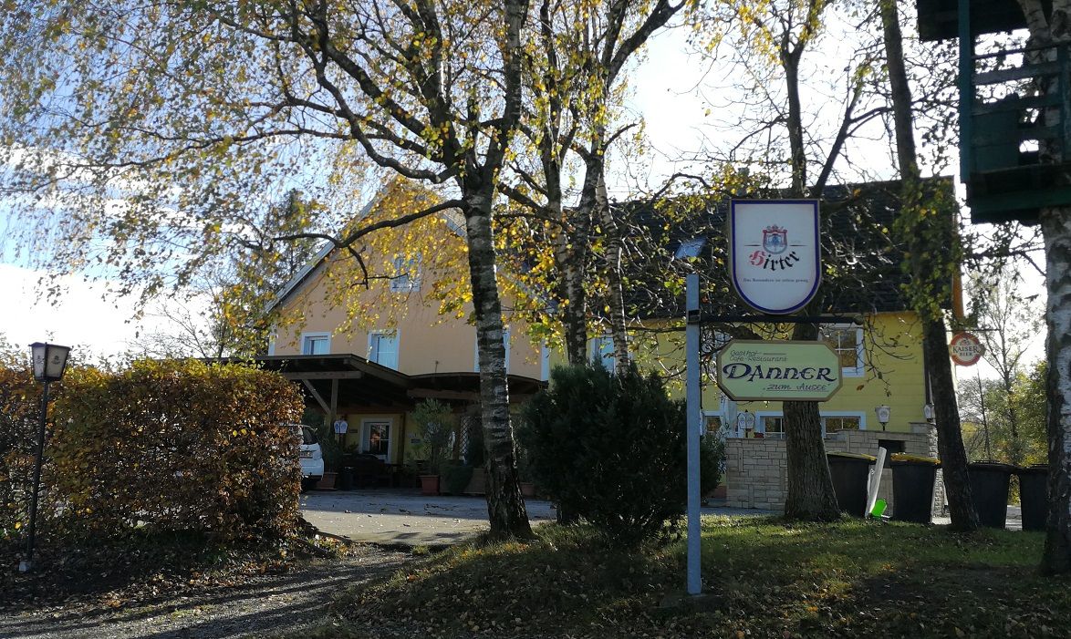 Gasthaus Danner mit Bäumen im Vordergrund und einem Schild.