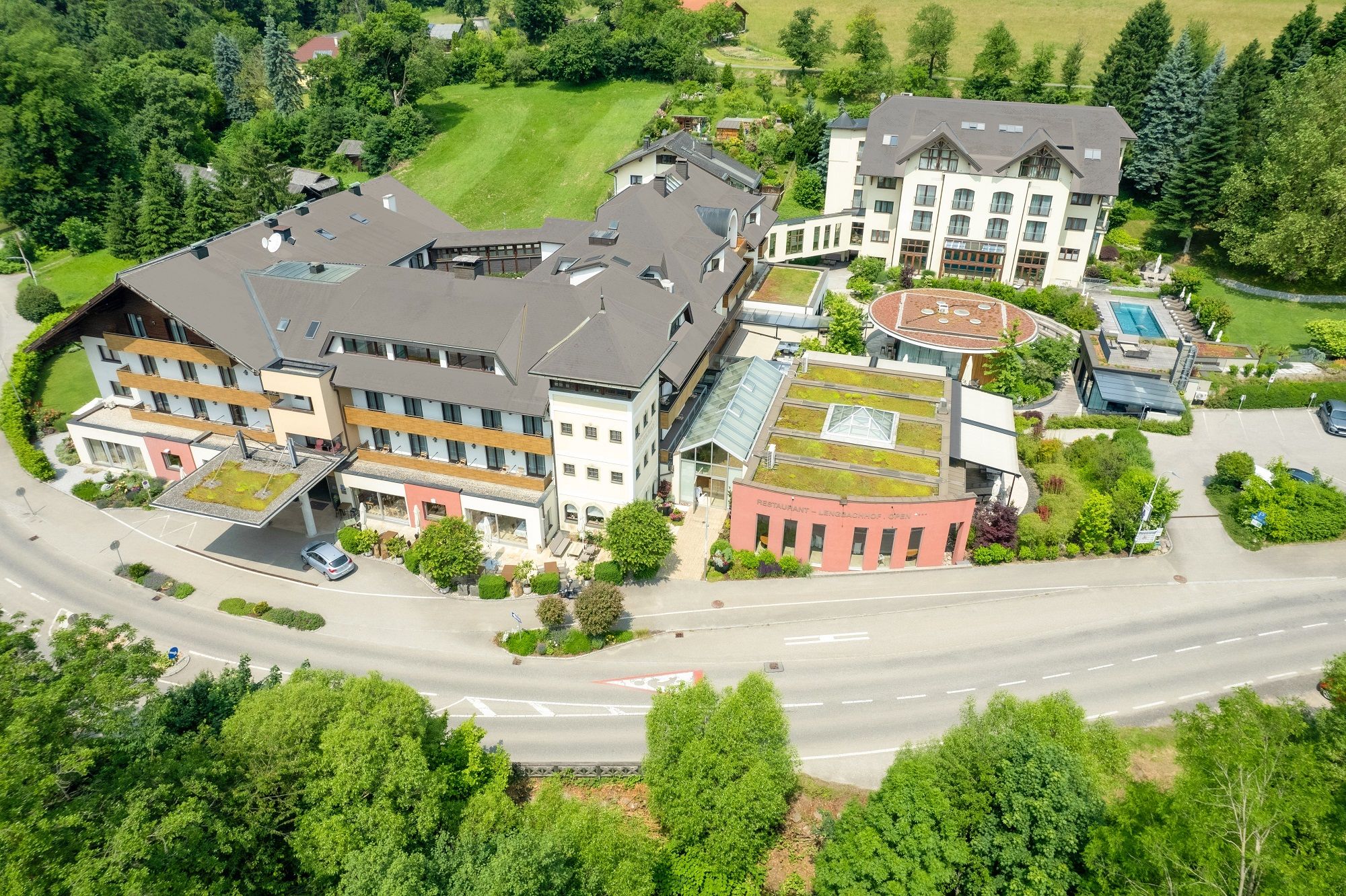Luftaufnahme eines großen Hotelkomplexes mit mehreren Gebäuden, umgeben von grüner Landschaft.