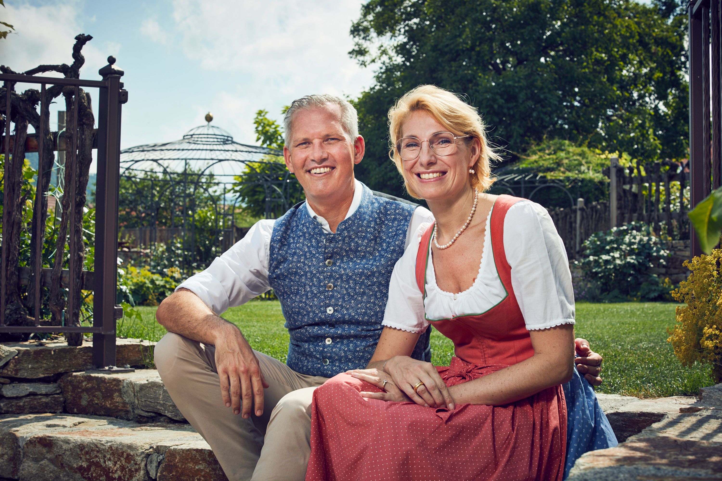 Familie Wildeis in Trachtenkleidung sitzen lächelnd im Garten.