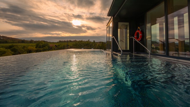 Infinity-Pool mit Blick auf die Landschaft bei Sonnenuntergang.