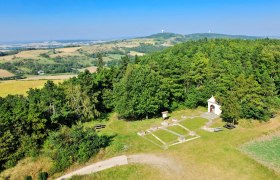 Landschaftsansicht von einem Aussichtsturm mit Wäldern, Feldern und einer kleinen Kapelle.