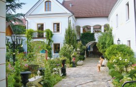 Ein idyllischer Innenhof mit Pflanzen und einer sitzenden Person.