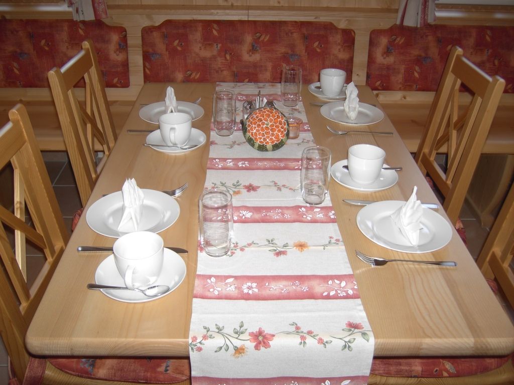 Ein gedeckter Tisch in einem Frühstücksraum mit Geschirr und Gläsern.