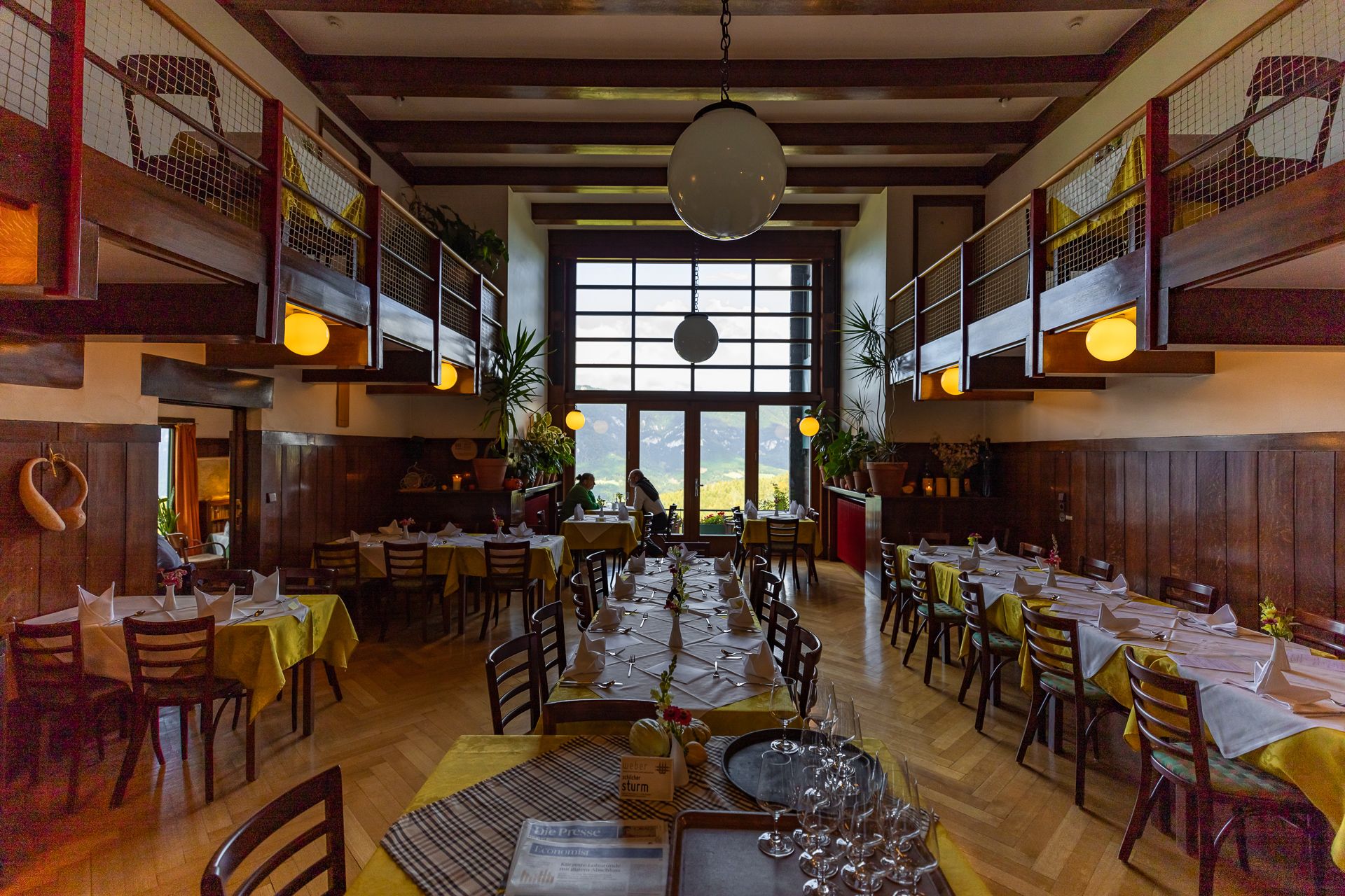 Innenansicht eines Restaurants mit Holzmöbeln und großen Fenstern.