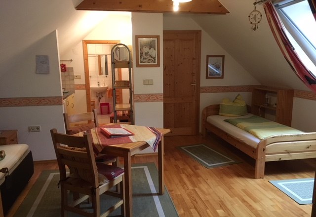 Gem&uuml;tliche Ferienwohnung mit Holzm&ouml;beln, zwei Betten, Esstisch und Dachfenster.