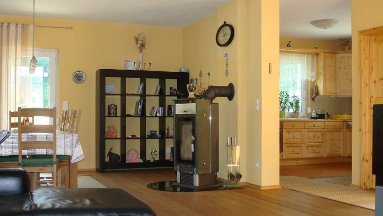 Wohnk&uuml;che mit Holzm&ouml;beln, Esstisch, Regal, Kamin und offener K&uuml;che.