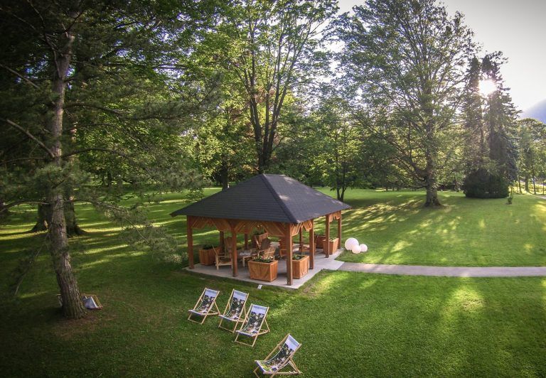 Ein Pavillon im Park mit Liegestühlen und Bäumen.