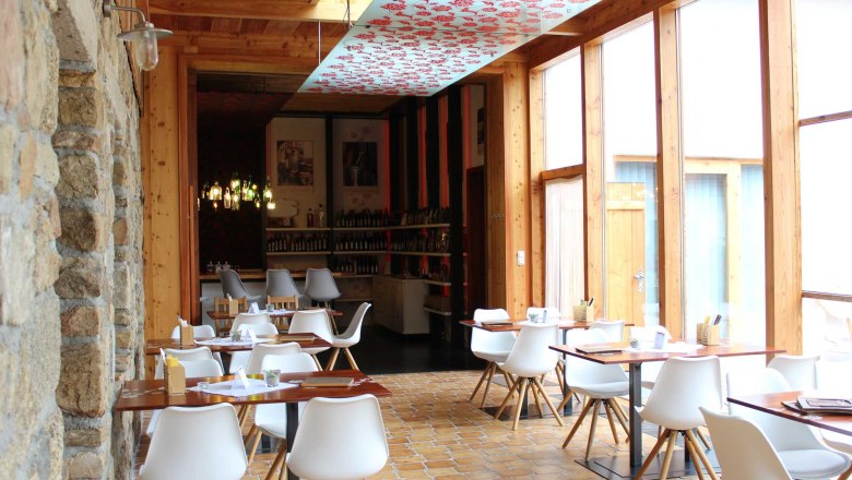 Innenansicht eines modernen Restaurants mit weißen Stühlen und Holztischen.