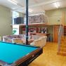 Ein Jugendraum mit Billardtisch, Sofas und einer Empore mit Treppe.