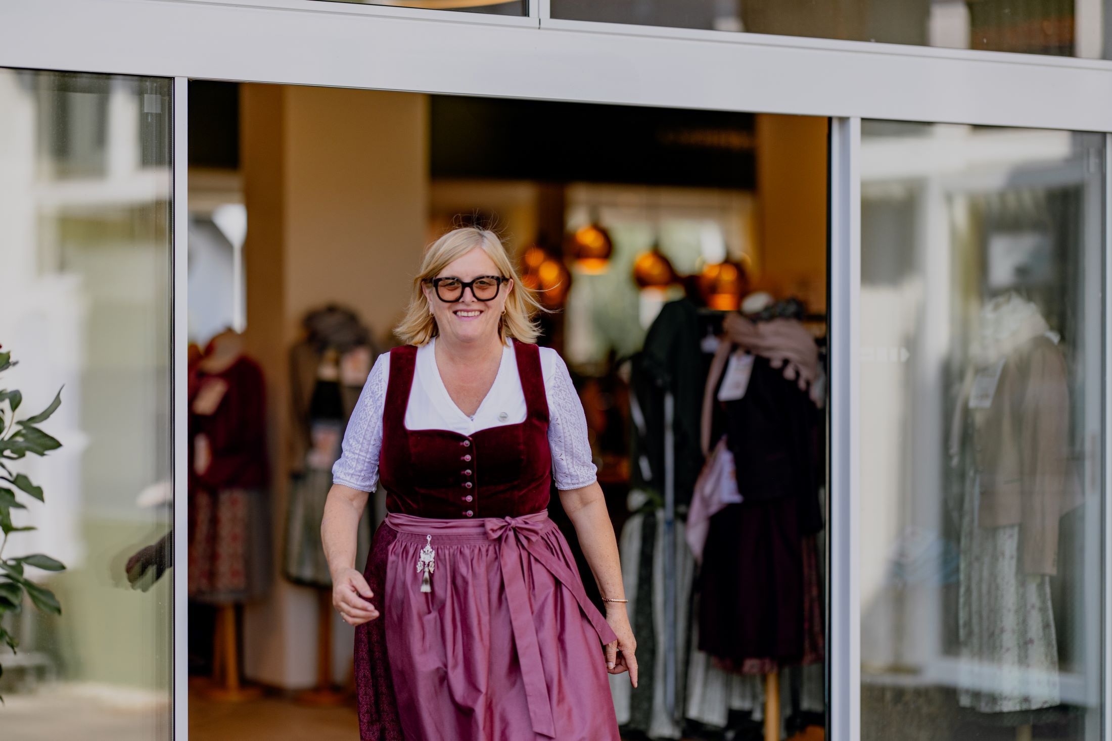 Frau in Tracht verlässt ein Bekleidungsgeschäft.