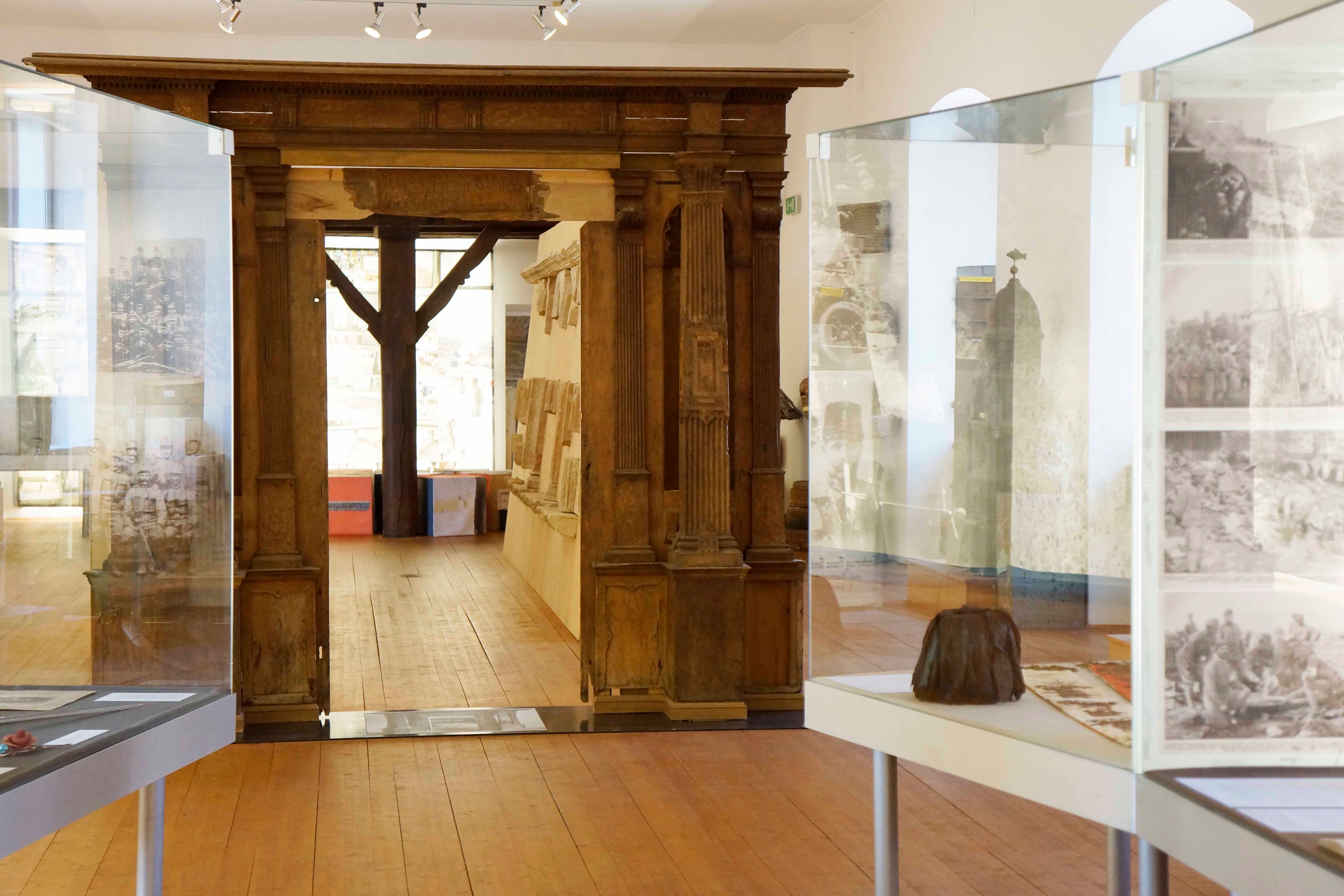 Innenansicht eines Museums mit Holztüren und Vitrinen.