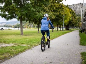 Eine Frau f&auml;hrt mit dem Fahrrad am Donauradweg bei Hainburg.