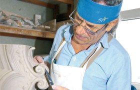 Ein Restaurator arbeitet an einem dekorativen Element mit einem Werkzeug.