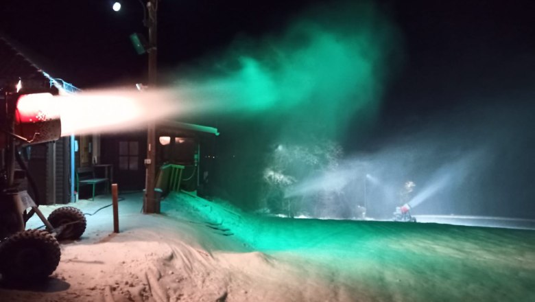 Schneekanone bei Nacht mit gr&uuml;nem Licht beleuchtet.