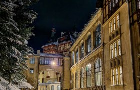 Historisches Gebäude im Winter bei Nacht, beleuchtet mit Schnee bedeckt.