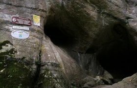 Eingang der Gudenush&ouml;hle mit Schildern an der Felswand.