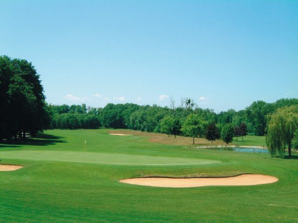 Golfplatz mit Sandbunker und grüner Landschaft.