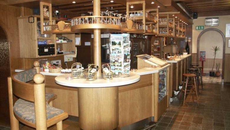 Innenansicht einer gemütlichen Bar mit Holzmöbeln und Theke.