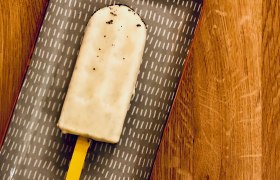Ein Eis am Stiel auf einem gemusterten Teller auf einem Holztisch.