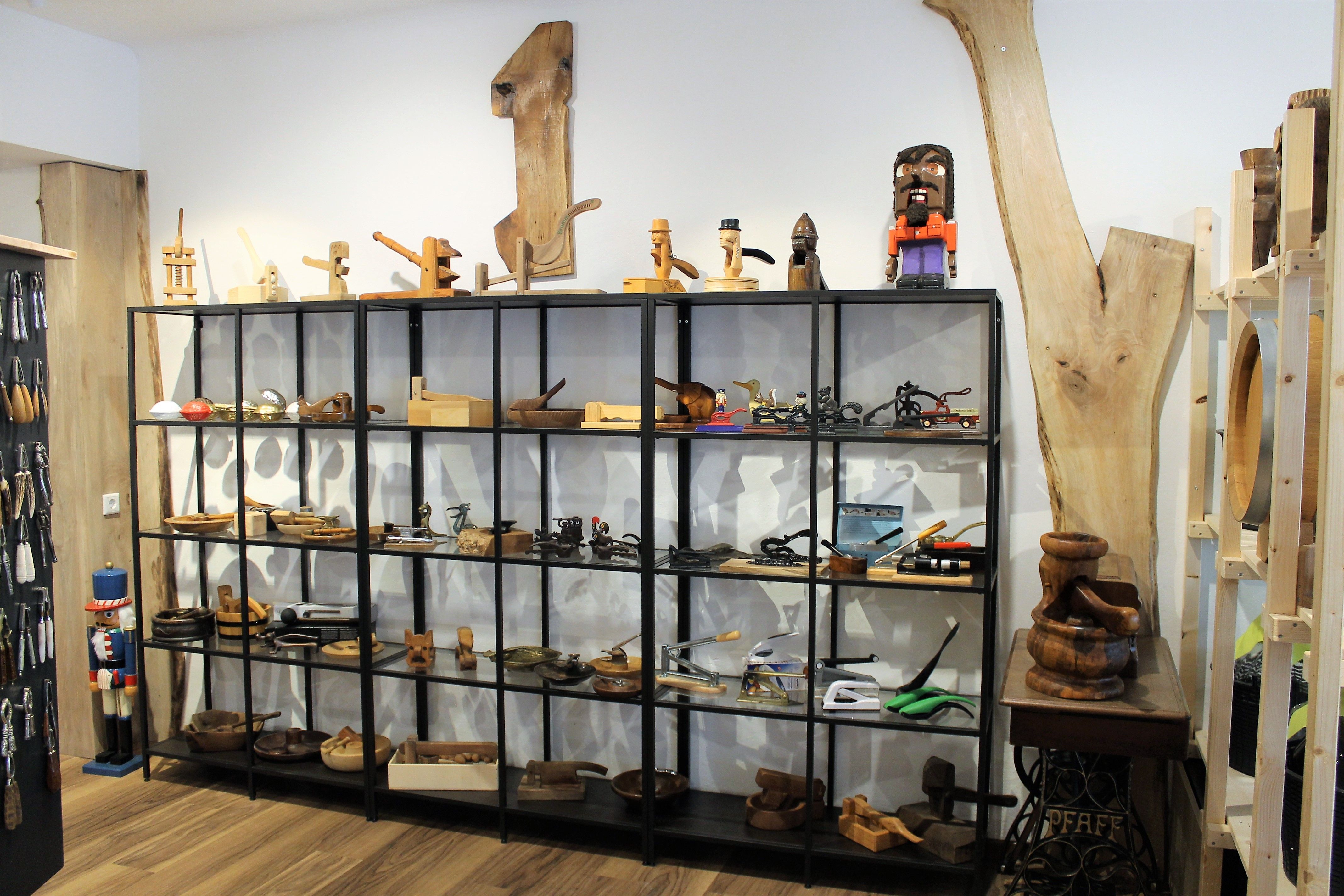 Regal mit Holzobjekten und Werkzeugen in einem Ausstellungsraum.