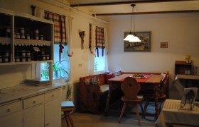 Gem&uuml;tliche K&uuml;che mit Holzm&ouml;beln und karierten Vorh&auml;ngen.