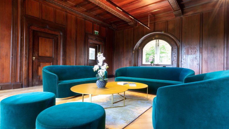 Elegantes Wohnzimmer mit gr&uuml;nen Sofas und Holzw&auml;nden.