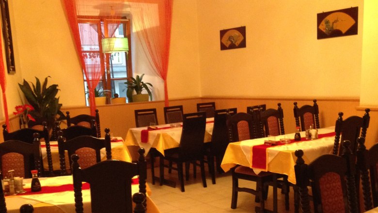 Innenansicht eines asiatischen Restaurants mit gedeckten Tischen und Stühlen.