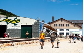 Eingang der Schneebergbahn am Hochschneeberg mit Menschen und Berghaus im Hintergrund.