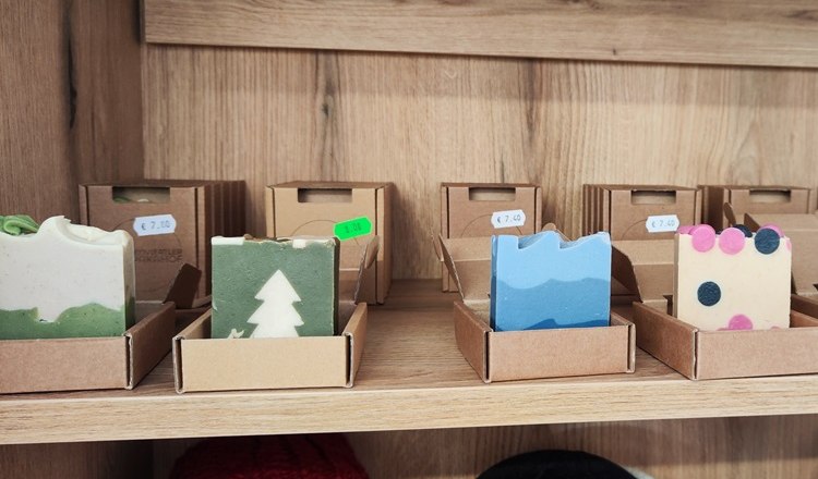 Handgemachte Seifen in verschiedenen Farben und Mustern auf einem Holzregal.