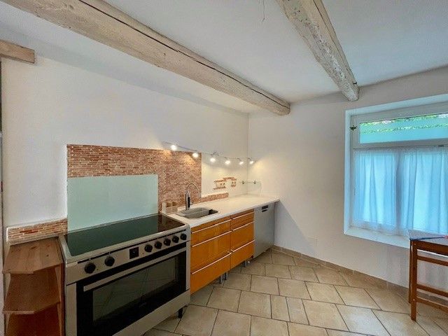 Moderne Küche mit Herd, Holzschränken und Fliesenboden.